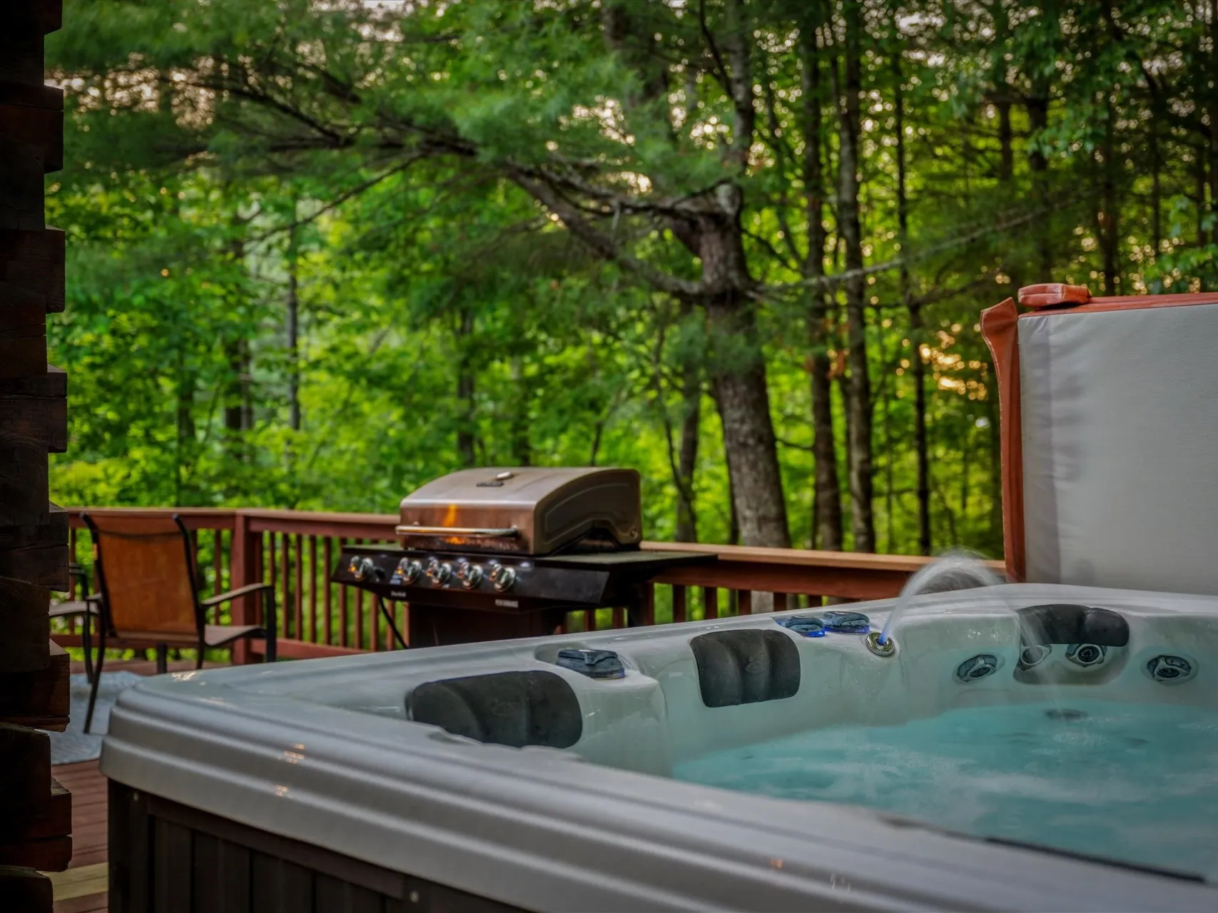 Covered hot tub at dusk on the deck, jets bubbling, looking out into the Pisgah forest