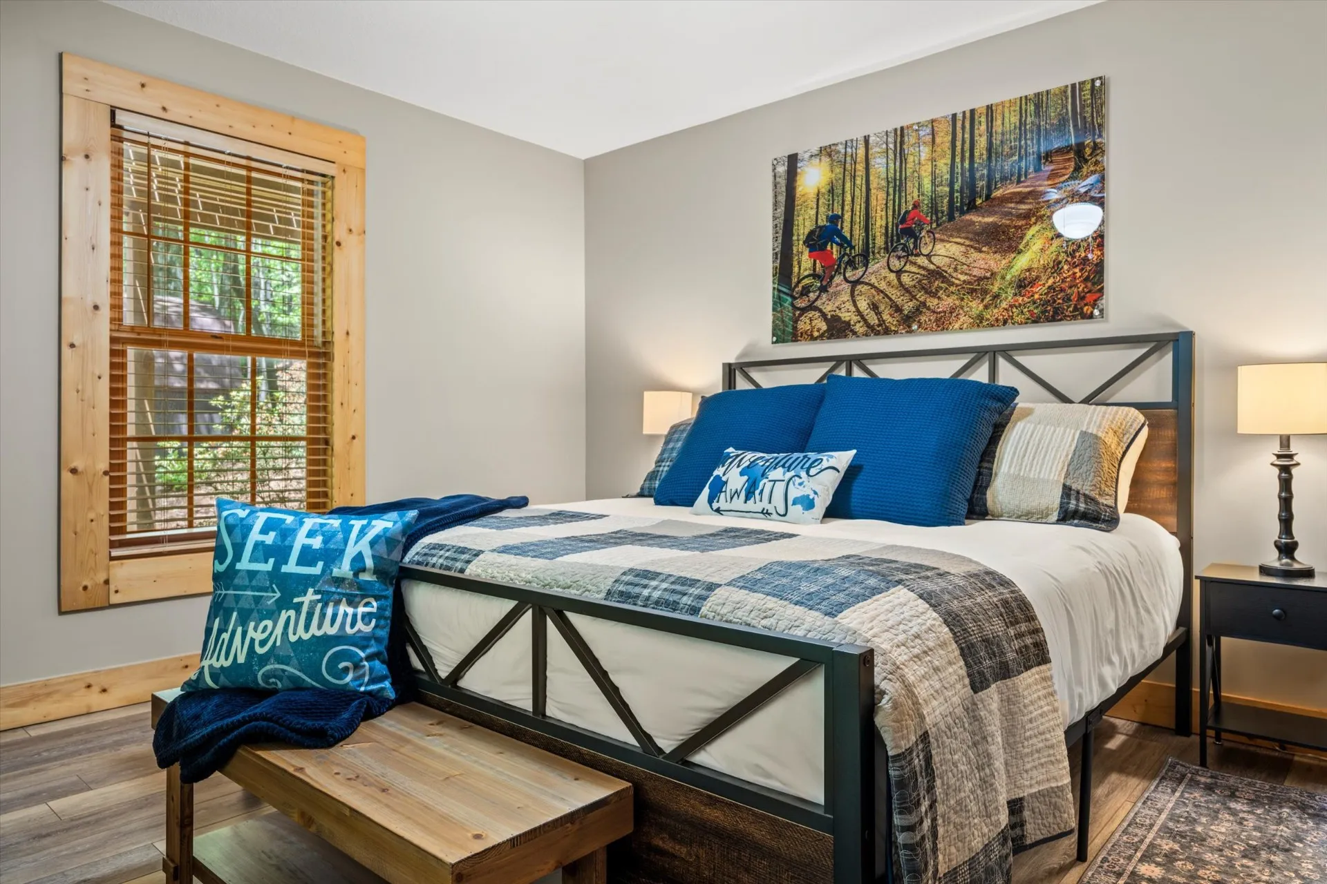 Ridgeline Room — king bed with iron frame, mountain biking photography over the headboard, and warm pine accents