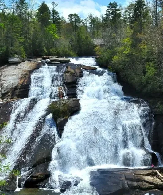 High Falls sliding down a tall granite wall in DuPont State Forest, with the covered bridge visible at the top